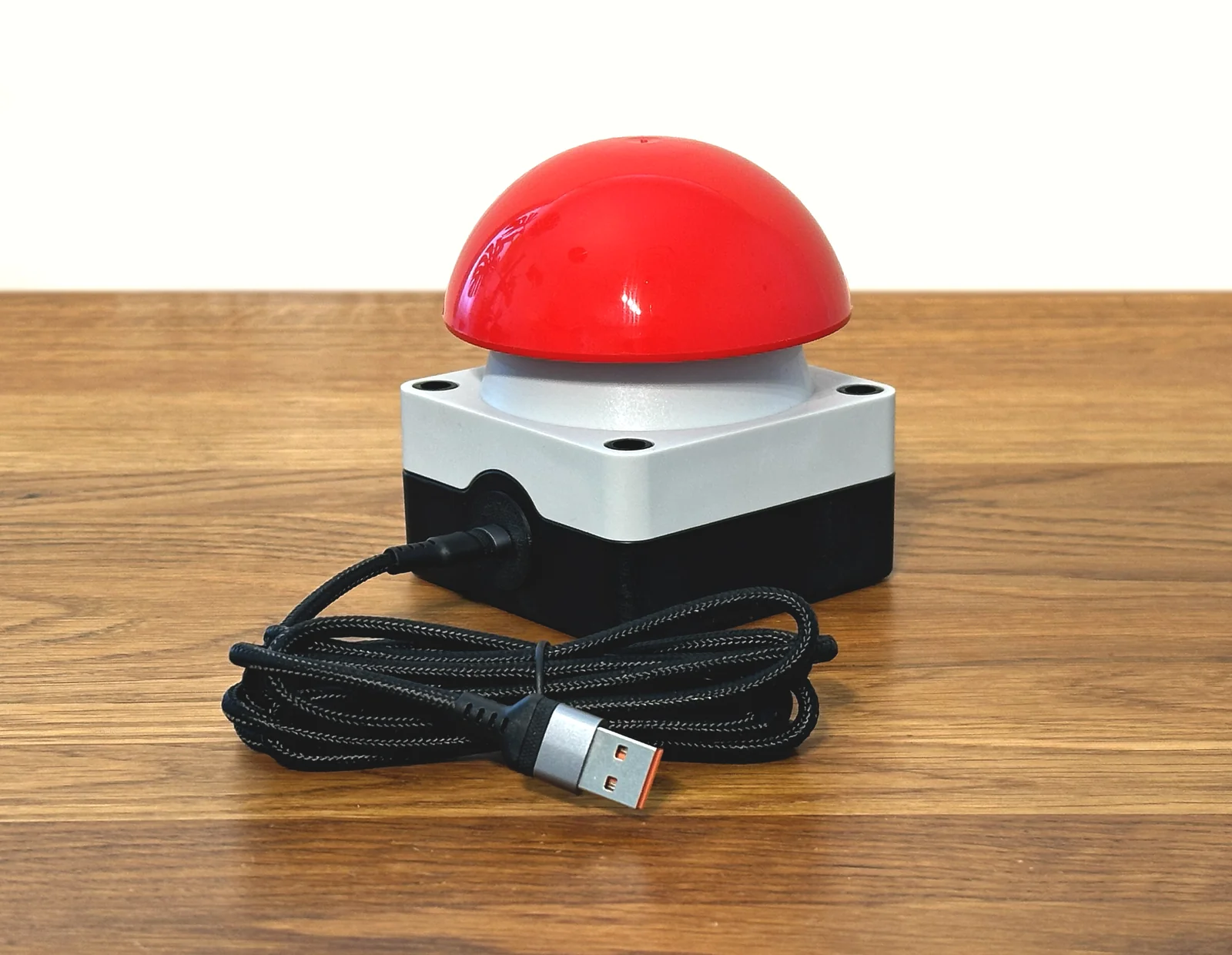 Roter USB-Buzzer mit Kabel auf einem Holztisch